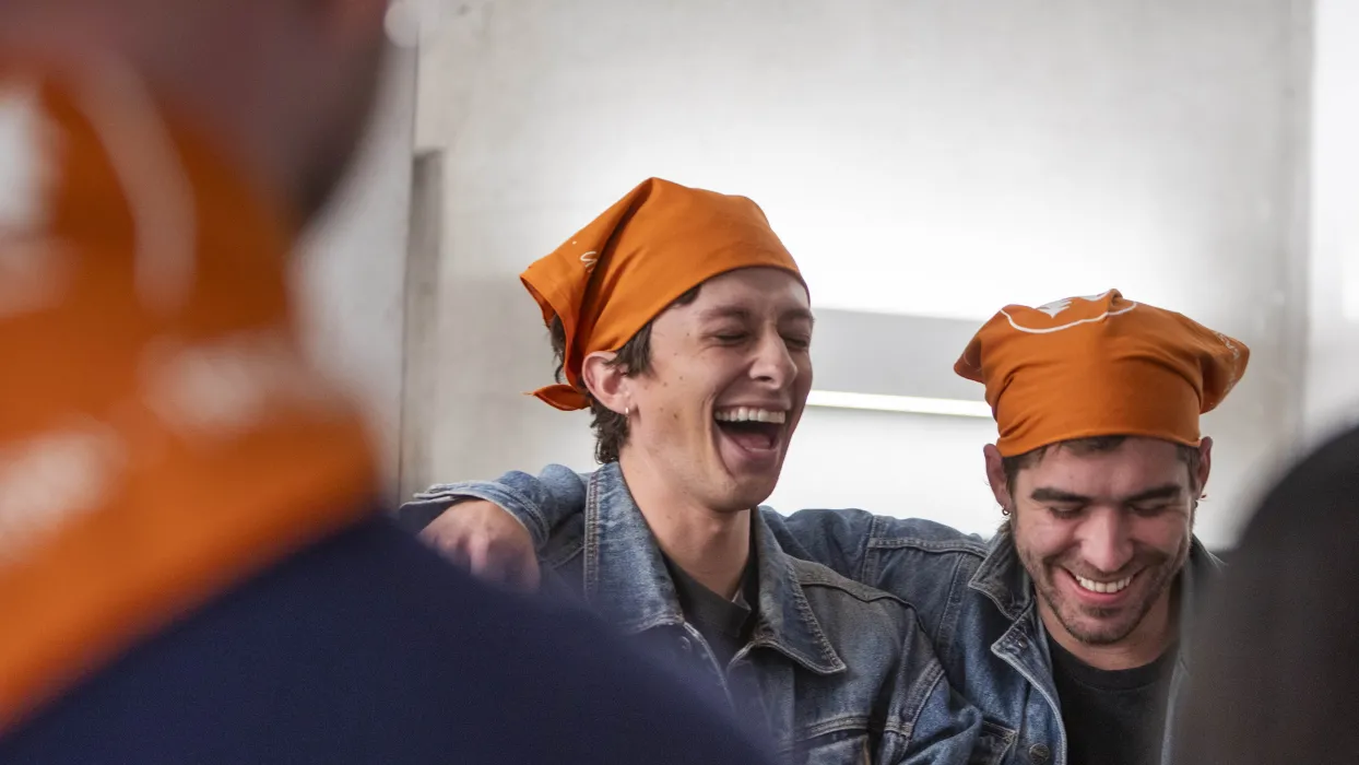 Two men laughing wearing orange bandanas on their head at the DBA Design Roundup.