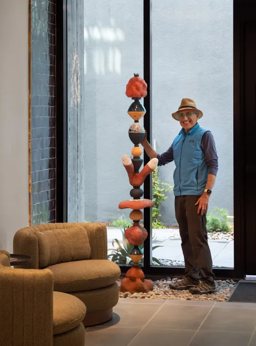 Man posting next to a sculpture.