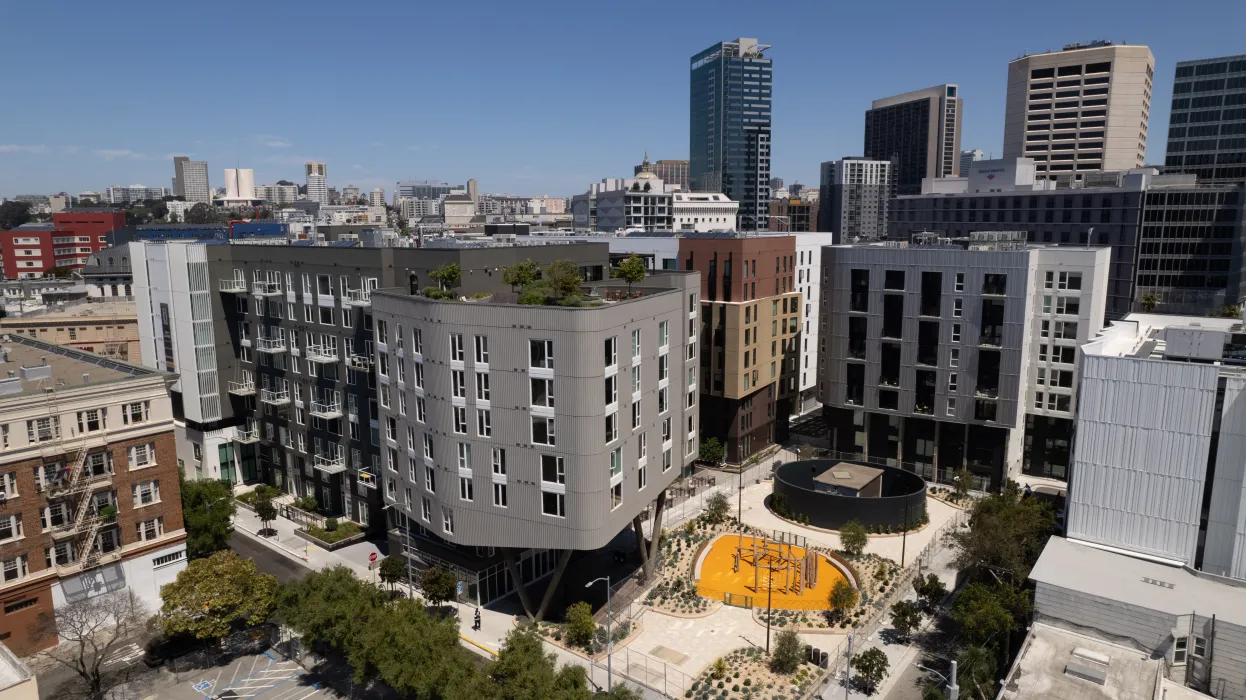 Aerial view of diverse buildings centered around a landscaped urban park with blue sky in background.