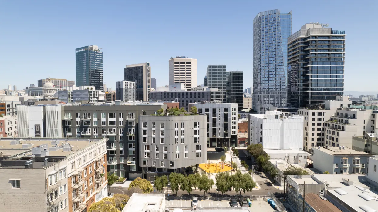 Aerial view of diverse buildings centered around a landscaped urban park with blue sky in background.