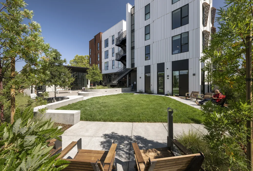 View of sunny central courtyard with small grass patch and seating.
