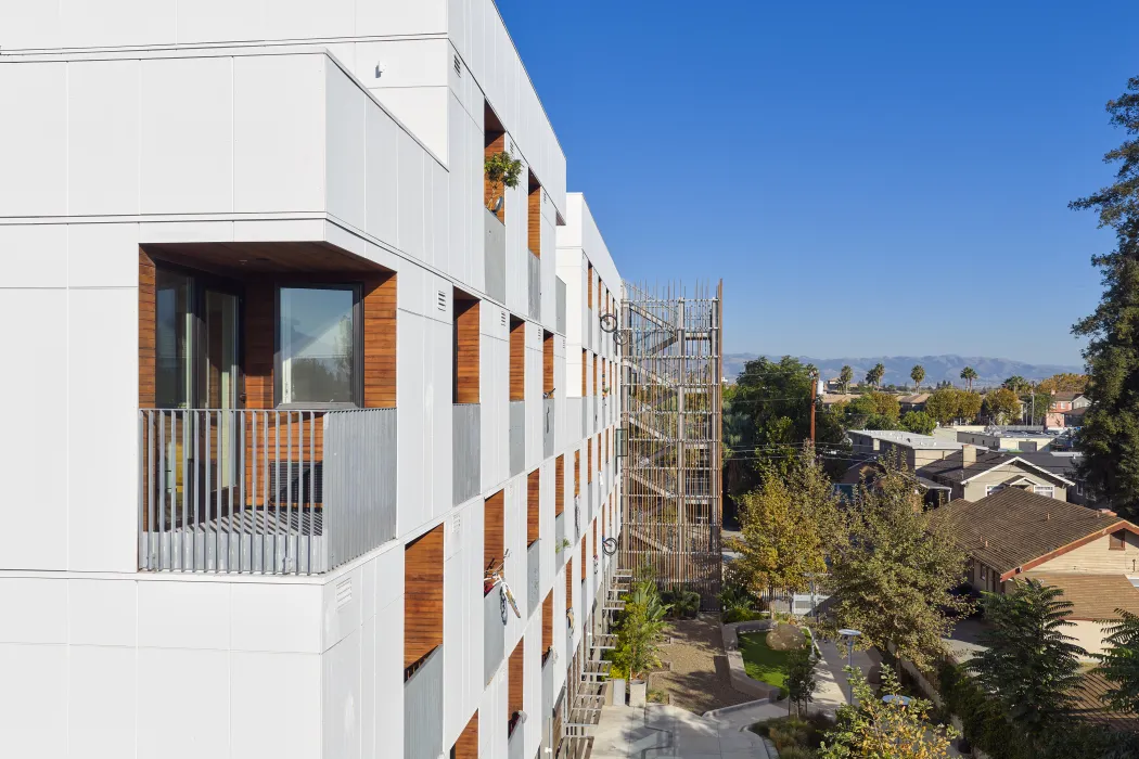 Close up corner view of balconies in checkerboard pattern in white apartment building against blue sky