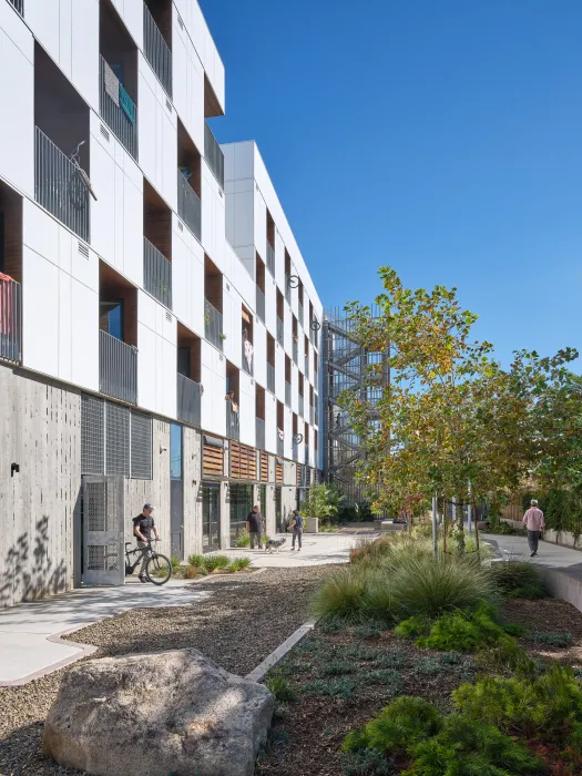 Courtyard of white apartment building with man exiting building with a bicycle