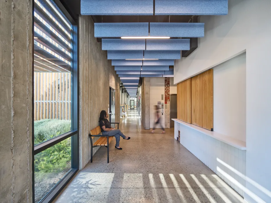 Interior view of apartment building lobby with bench, reception desk enclosed with wood doors, and elevator
