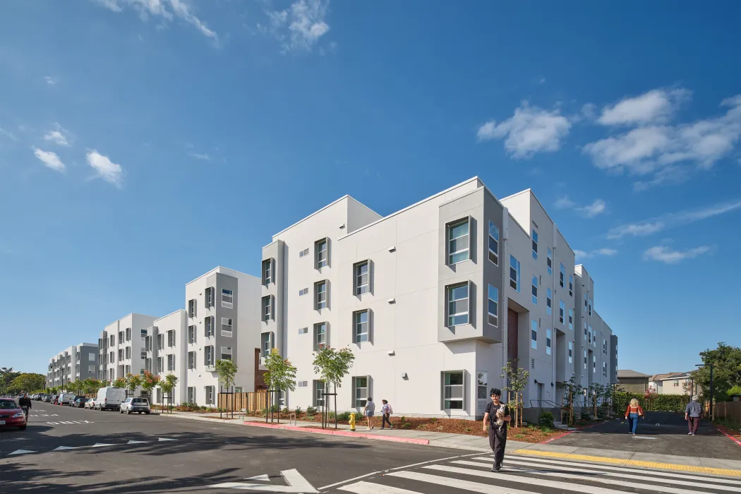 Large white building viewed from corner crosswalk against bright blue sky