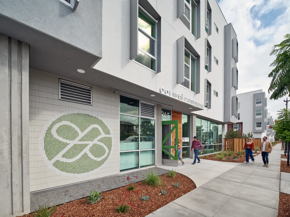 View from sidewalk of entry plaza with green hummingbird mural and bright green front door