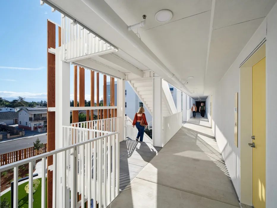 View from open-air hallway with yellow door and entry point to stair tower