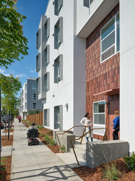 Stoop connecting to sidewalk, with two women talking and a man in a scooter on the sidewalk