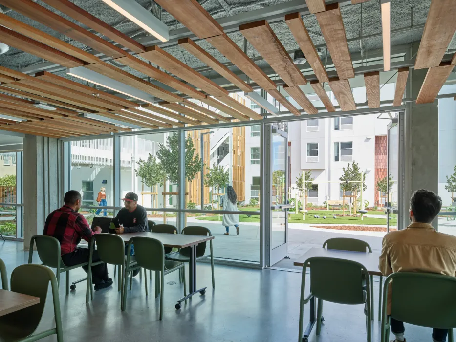 Community room with people working at tables with view out toward courtyard
