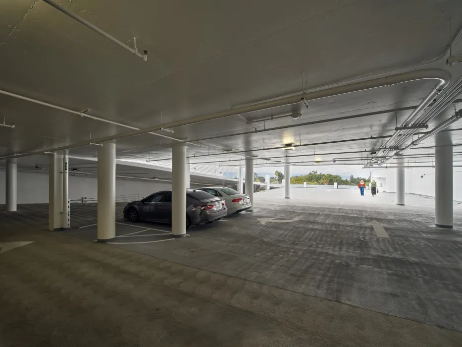 Two people in distance walking down parking ramp in a concrete garage