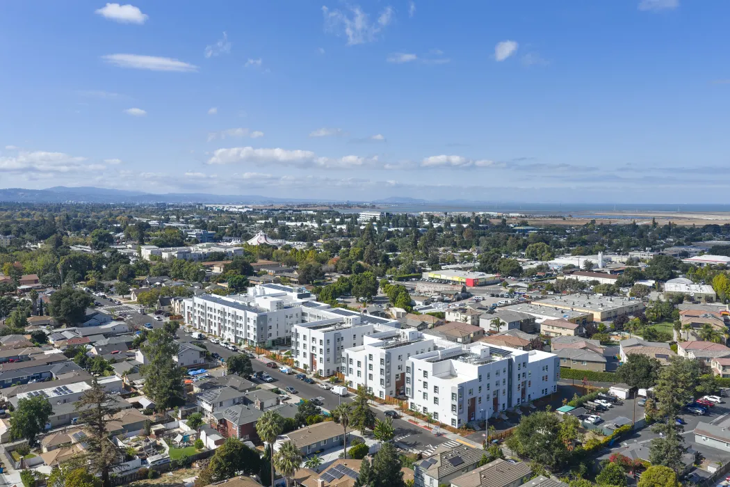 Oblique aerial view of large white building set in an urban context