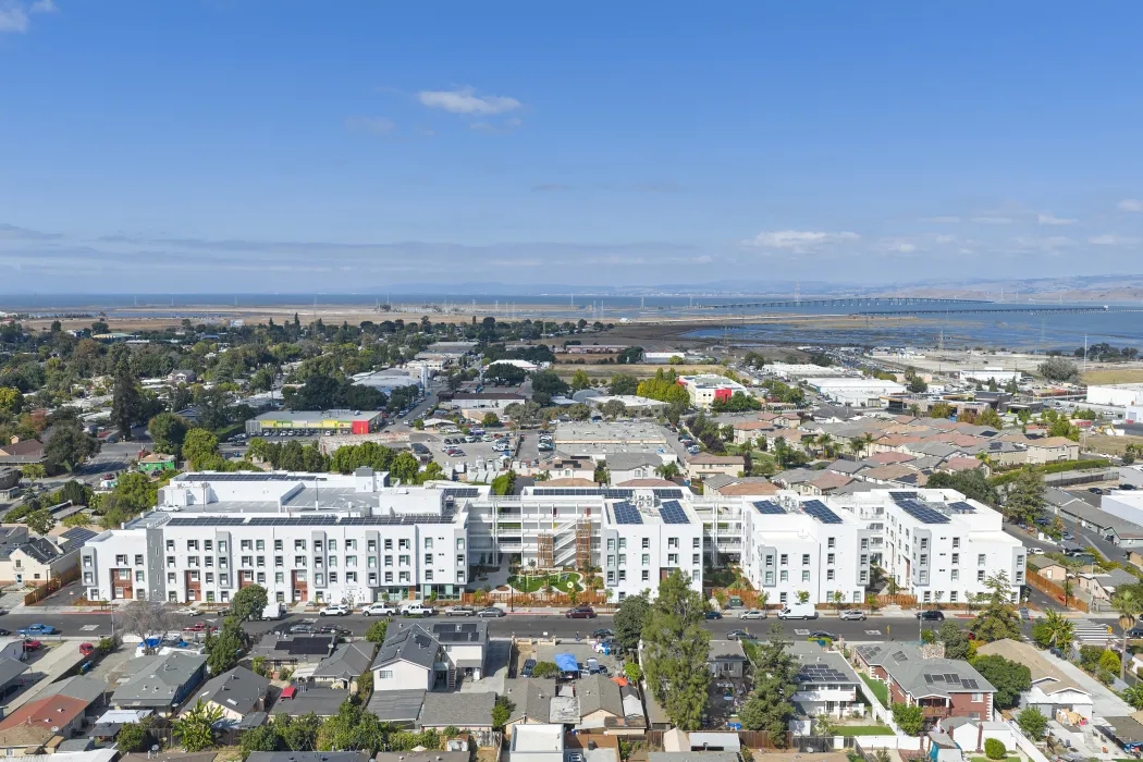 Straight-on aerial view of large white building set in an urban context
