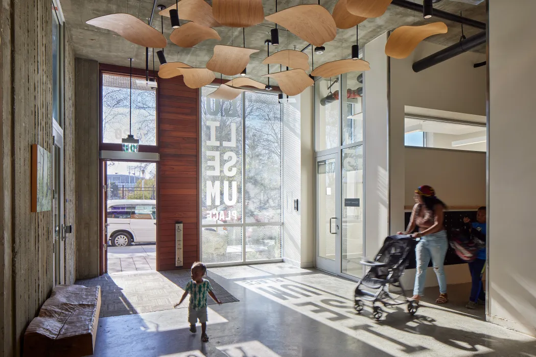View out through the glass face of an apartment building lobby with a sculptural wood ceiling