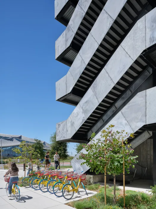 Gray exterior stair against blue sky with bikes parked in front 