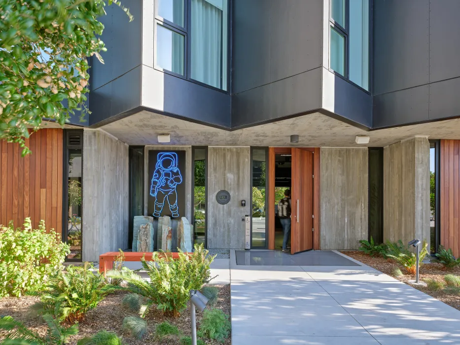 Gray building with man walking through brown wood door