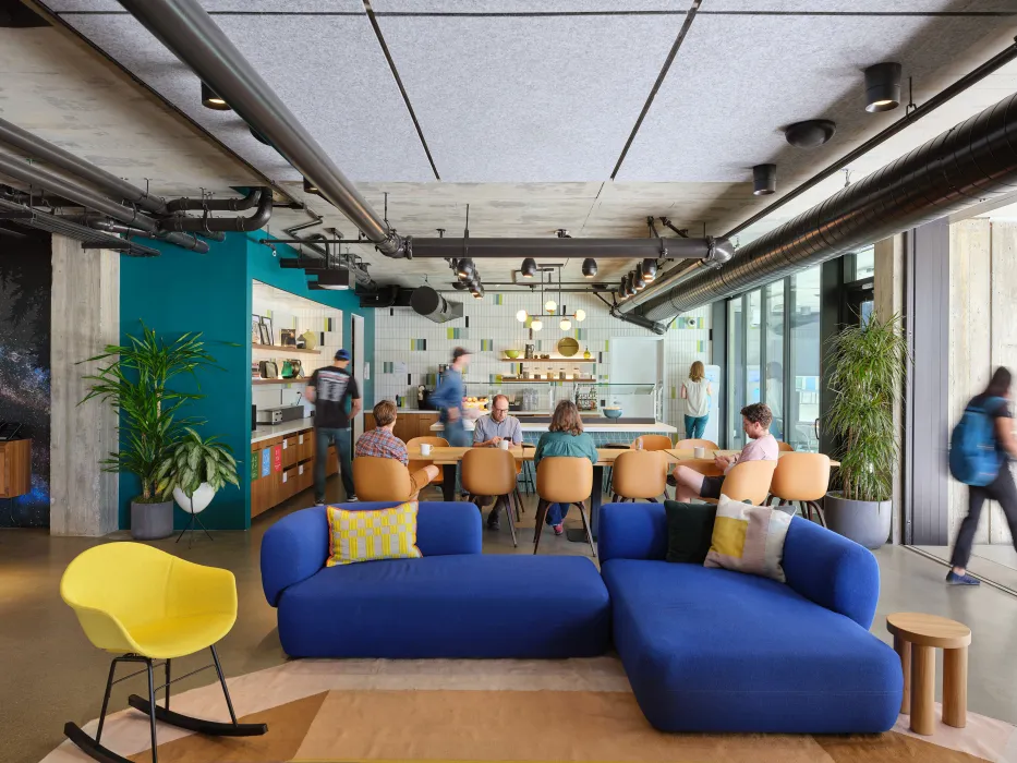 Lounge space with large dining table and blue sofa in foreground