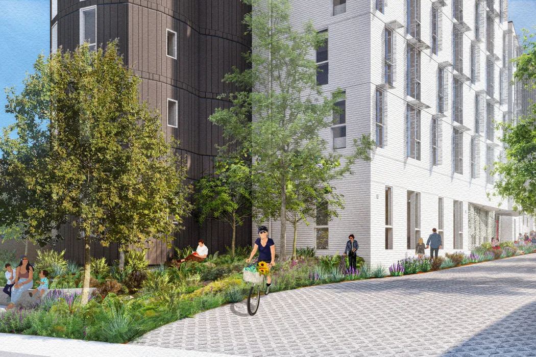 Woman on bicycle in front of gray and white building and garden plants