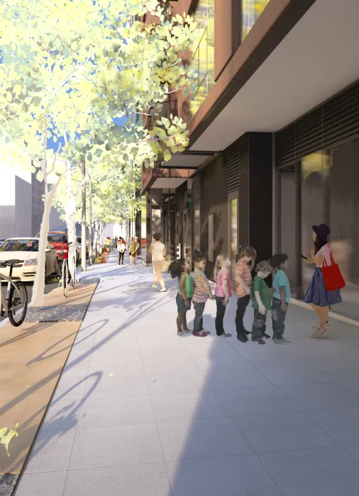 Children in a line on the sidewalk with woman talking and building in the background