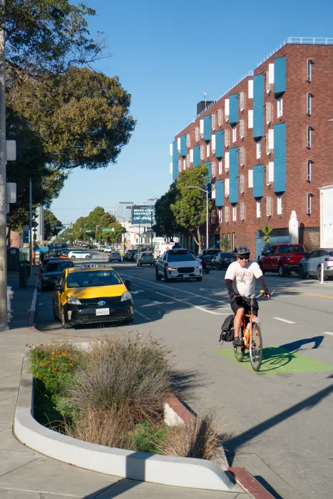 Red brick apartment building with cyclist and taxi in foreground