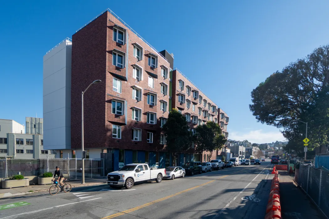 Street view of red brick apartment building with angular accents