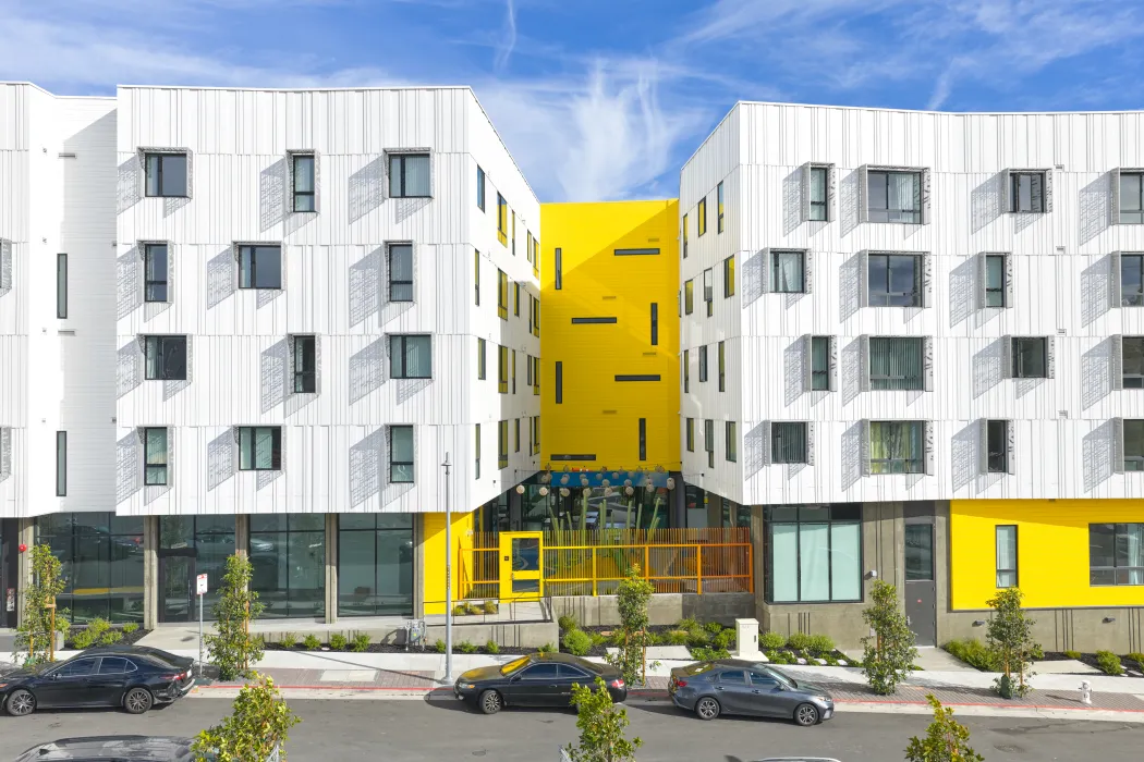 Street view of apartment building and yellow wall with slender windows
