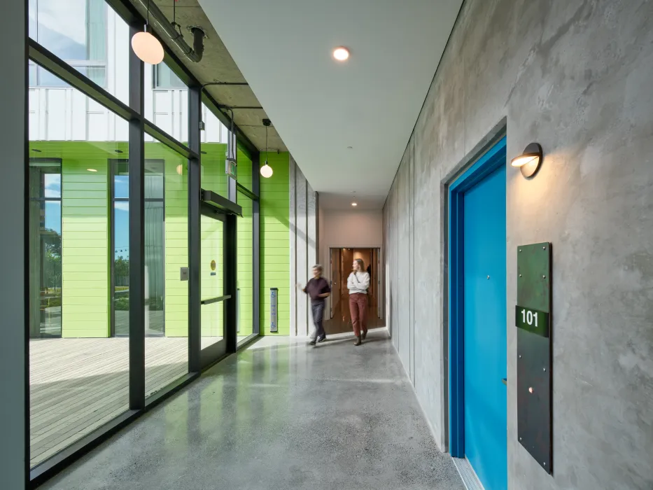 Ground floor unit door on right; daylight hallway with people