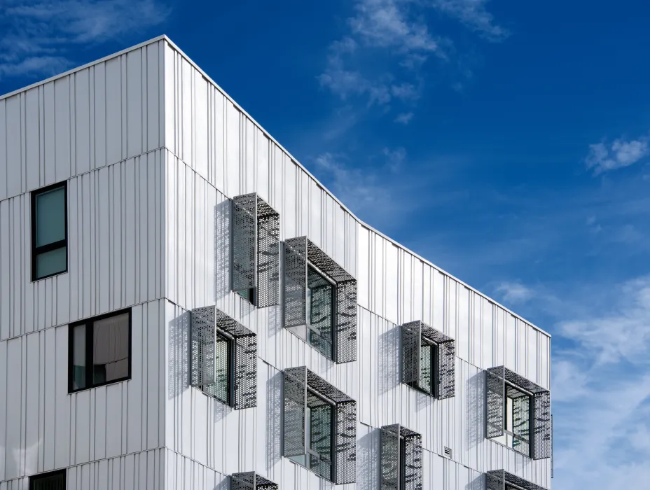 Detail view showing the perforated metal sunshades around the apartment windows