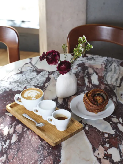 Coffees and a pastry on a small marble-topped table