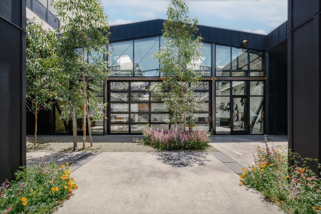 View of building with black steel framing and glass from a gravel courtyard