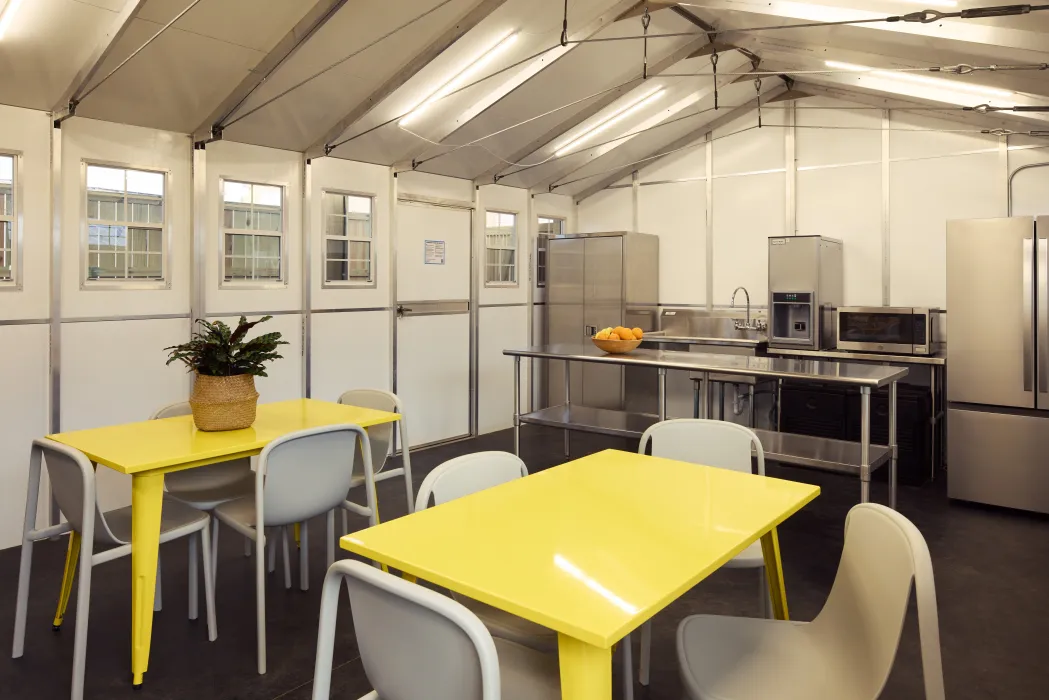 Interior of prefab kitchen structure with bright yellow tables