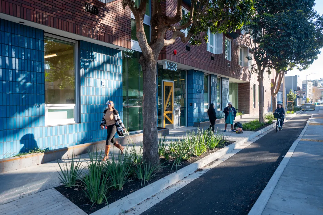A woman walks by the yellow entry door to a multifamily building