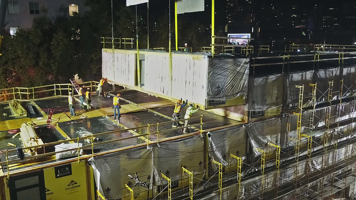 Modular construction night scene, crew placing a module