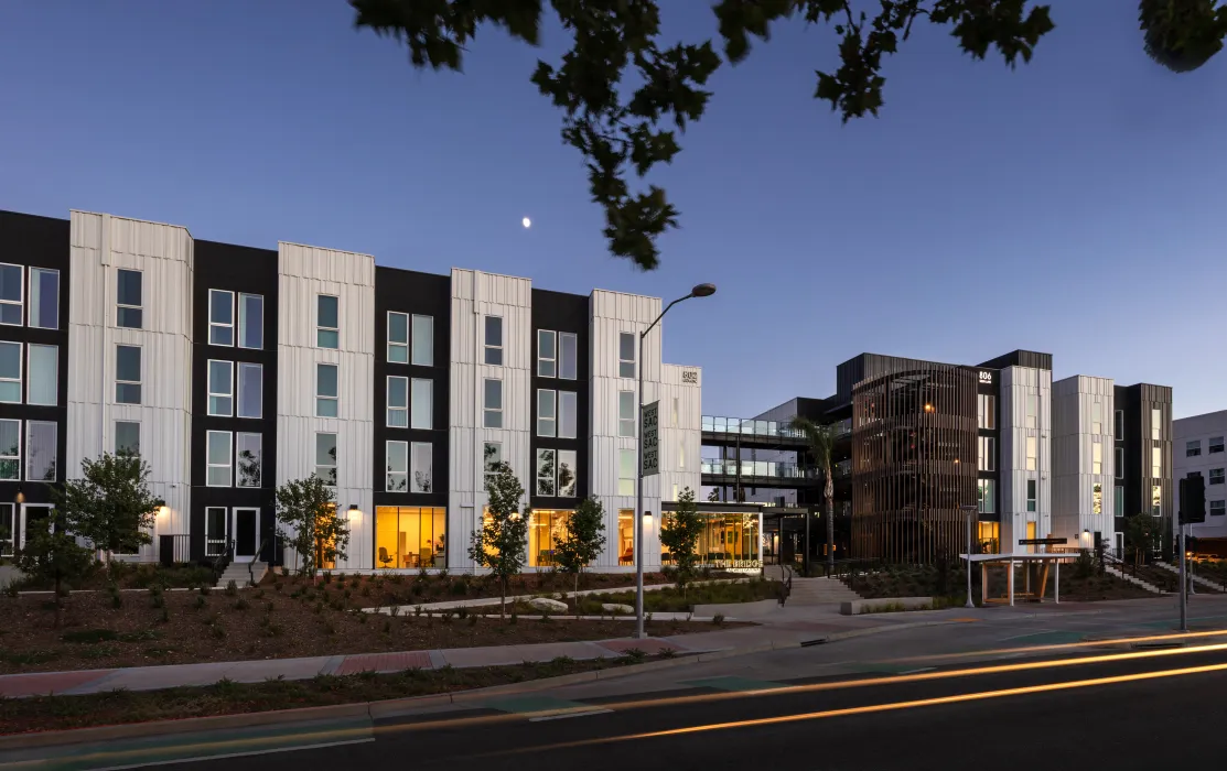 Elevation of multifamily building with black and white vertical bays taken just past dusk