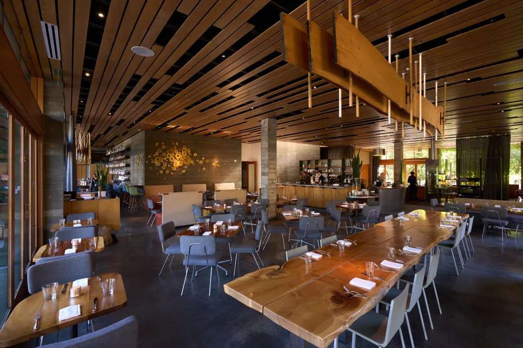Interior of a restaurant at dusk with custom wood ceiling, lighting, and host stand