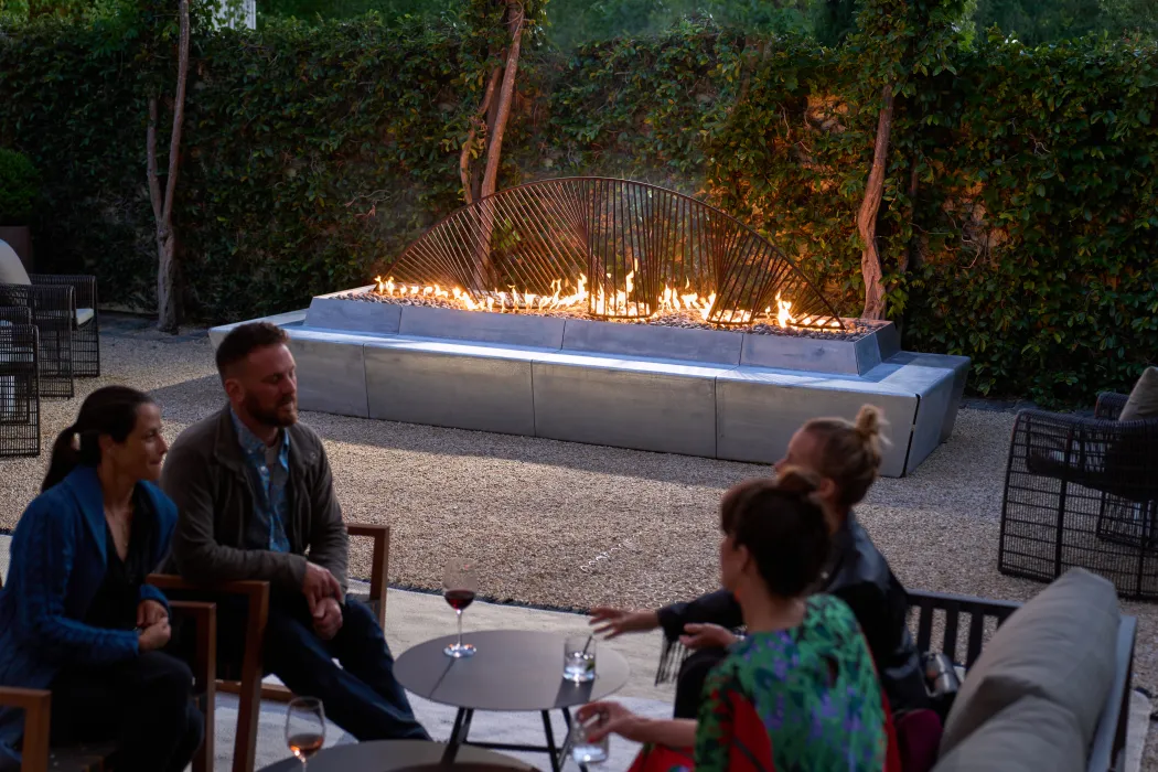 Sculptural concrete and steel fire feature with flames with seating area in front